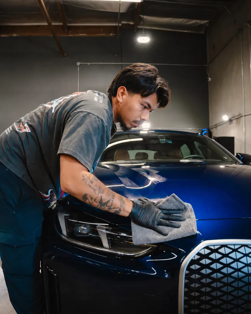 Wiping down a freshly coated blue BMW to a deep gloss