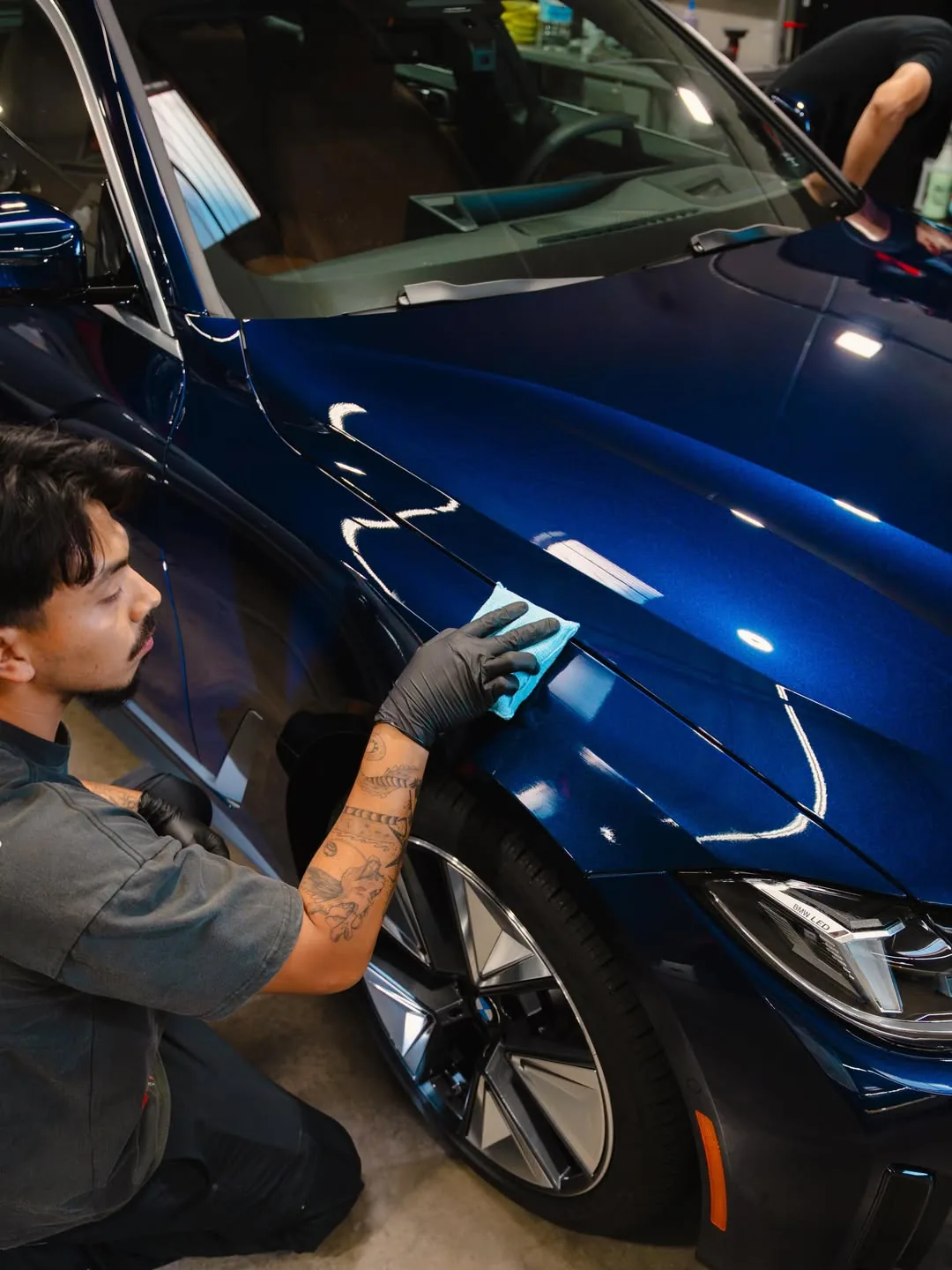 Hand-applying ceramic coating to a glossy blue BMW