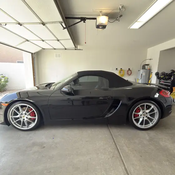 Black Porsche Boxster parked in a garage after a detail