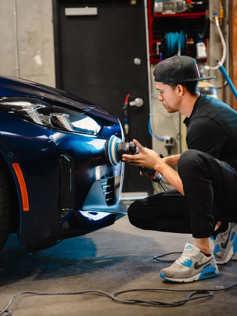 Machine polishing the front of a blue BMW before ceramic coating