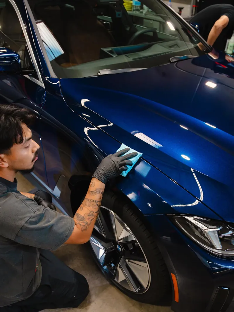Hand-applying ceramic coating to a glossy blue BMW
