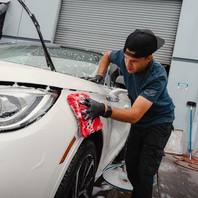 Detailer hand-washing a vehicle with foam on location