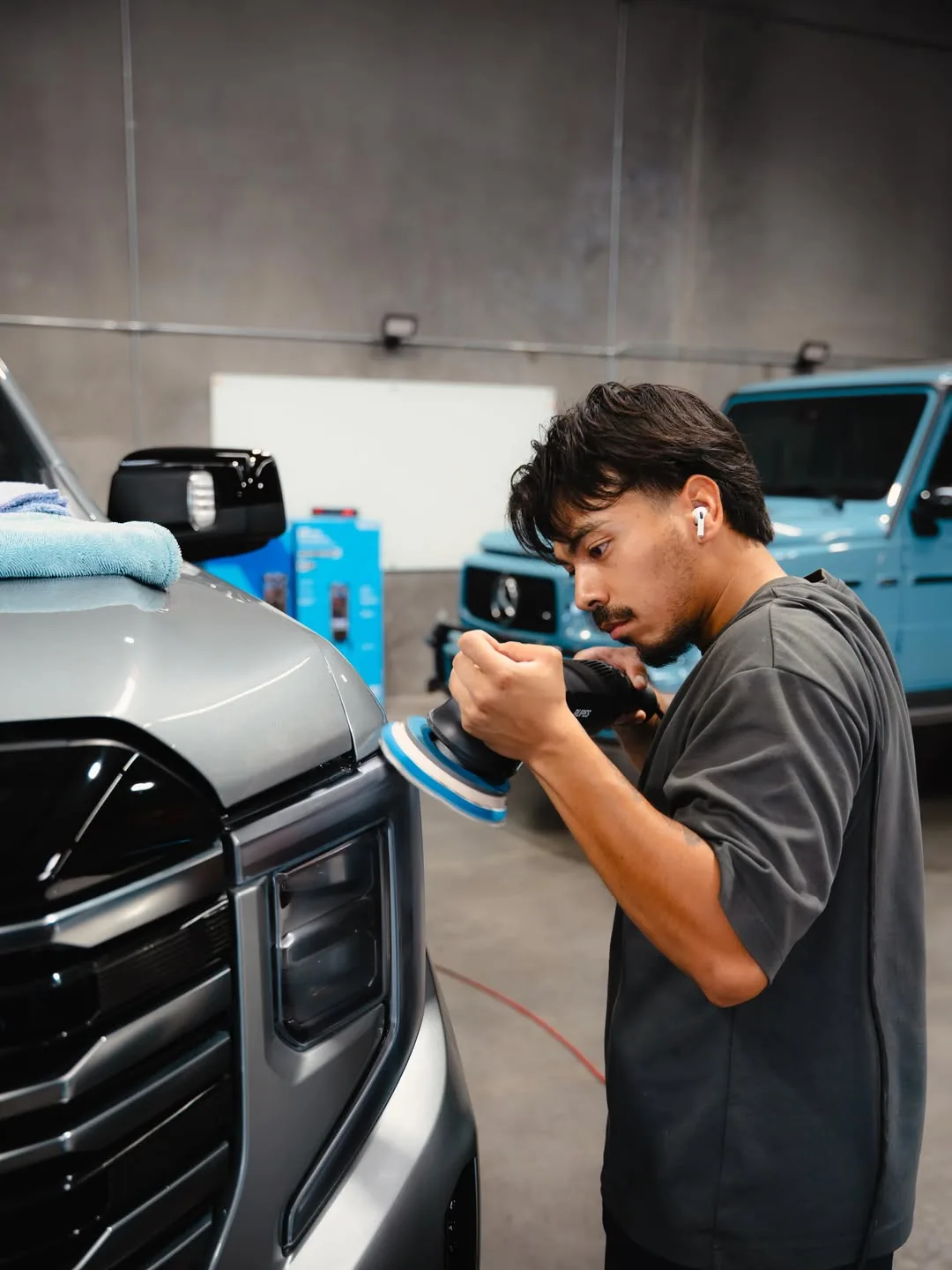 Detailer machine-polishing the front of a silver truck during a paint correction