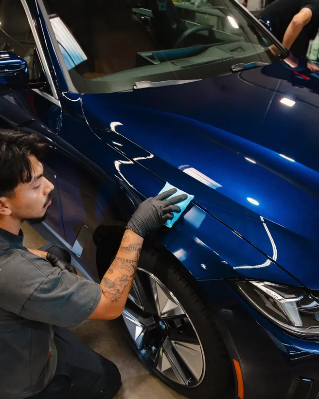 Marrufo Detailing team member detailing a blue luxury car by hand