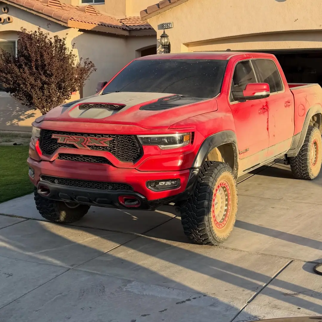 Red Ram TRX in a driveway before the detail, covered in dust and mud