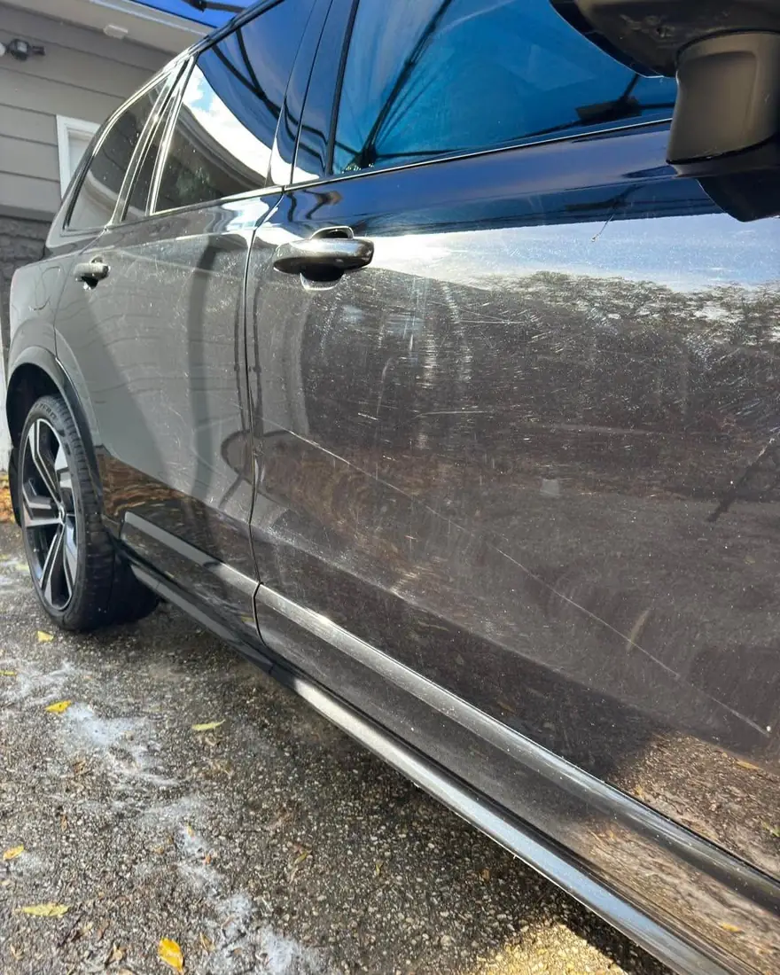 Black SUV door with swirl marks and haze