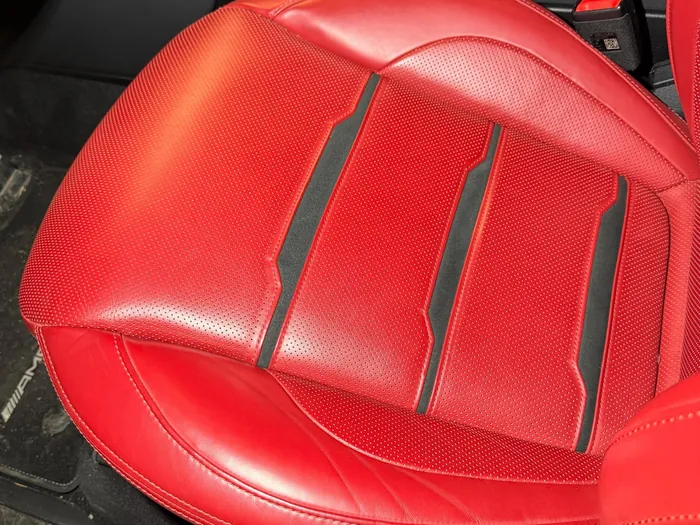 Red leather seat before, shiny with grime
