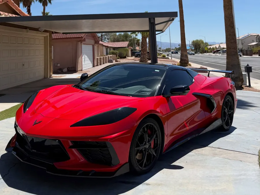 Red Corvette Stingray with glossy paint parked under palm trees