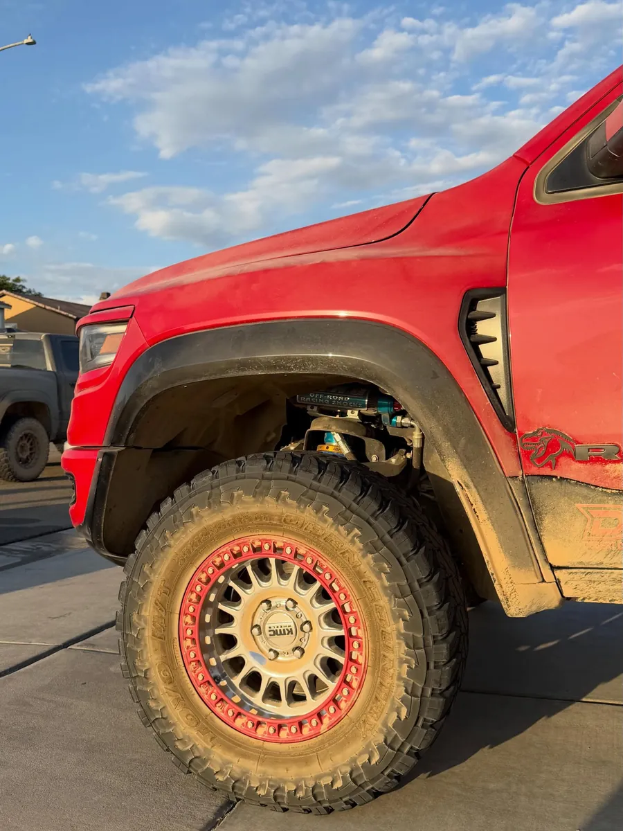 Red pickup wheel and fender covered in dried mud