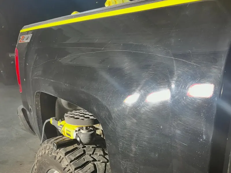 Black truck fender covered in swirl marks and scratches